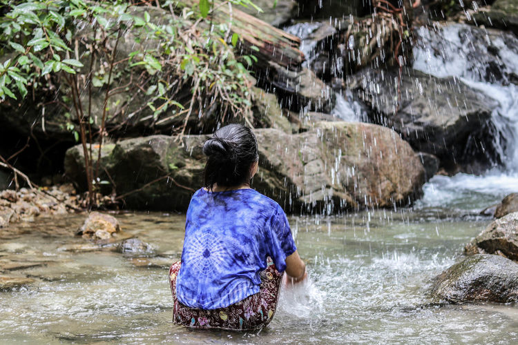 Rear view of woman splashing water in river