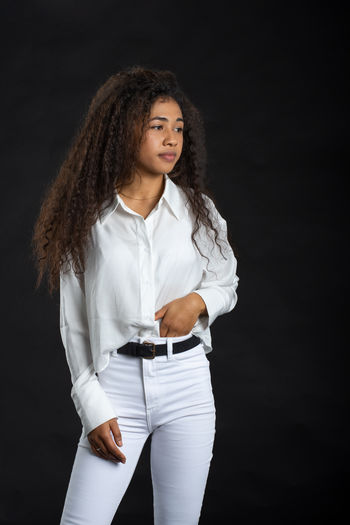 Young woman standing against black background