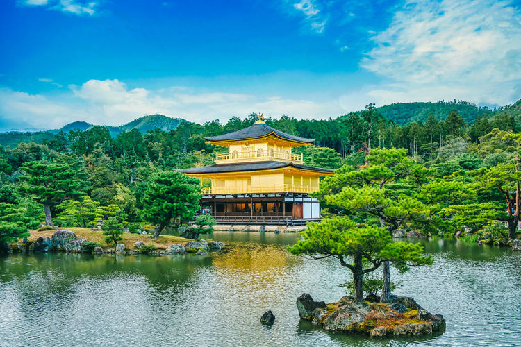 Famous golden temple in kyoto by lake and against sky