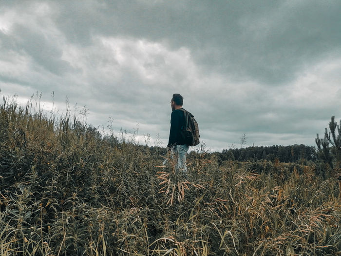 Rear view of man standing on field against sky