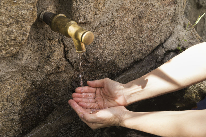 Woman's hands picking water from a fountain spout