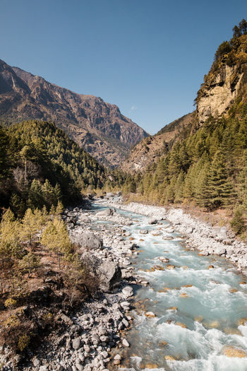 Scenic view of river stream amidst mountains against clear sky