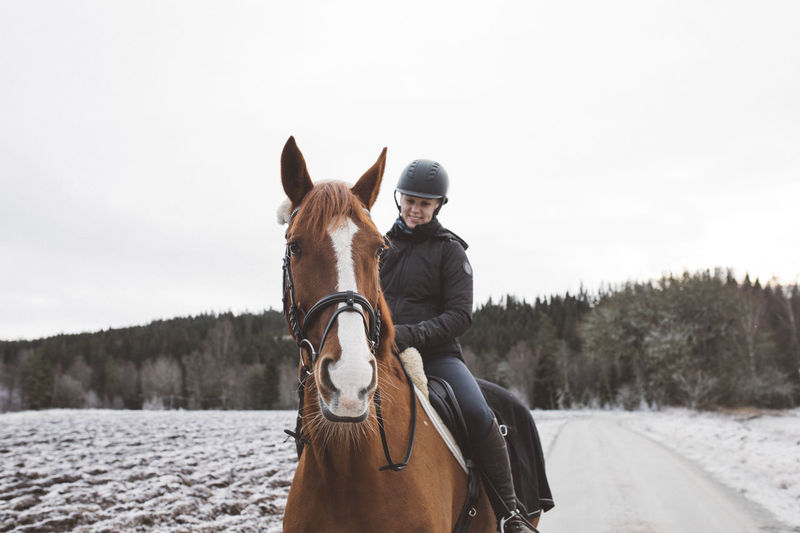 Smiling woman horseback riding