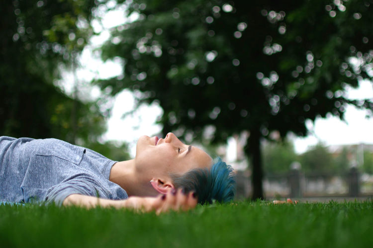 Side view of woman lying on field at park