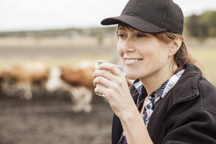 Mid adult female farmer drinking milk in farm
