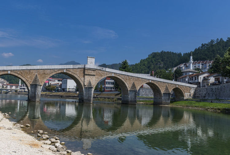 Arch bridge over river against sky