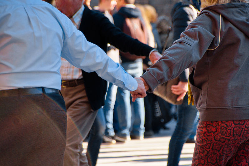 Rear view of friends standing on street holding hands while traditional dance, mallorca