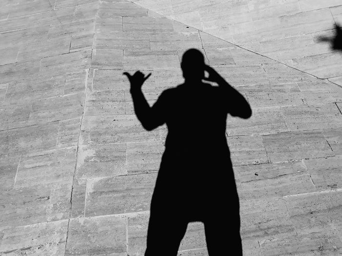 Silhouette man standing on street against wall
