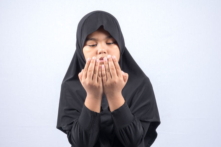 Girl in hijab praying over white background