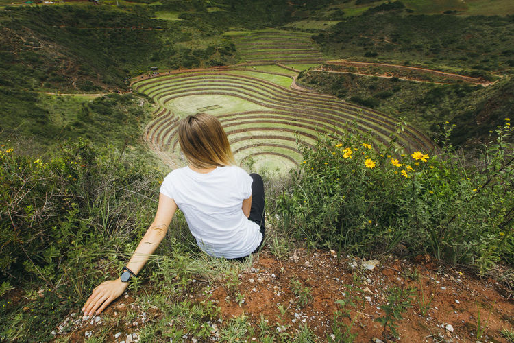 A young woman is sitting near the famous peruvian spot moray in peru