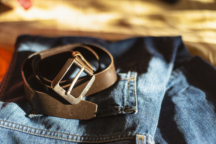 Men's brutal accessories, belt on a dark background with blurred depth of field brown belt and denim