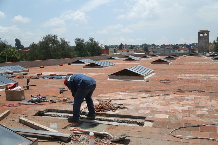 Man working on roof of building against sky