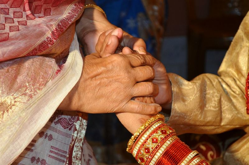 Close-up of mother holding bridegroom hands