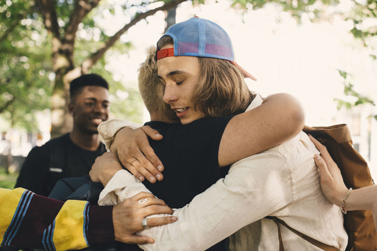 Hipster embracing male friend in park