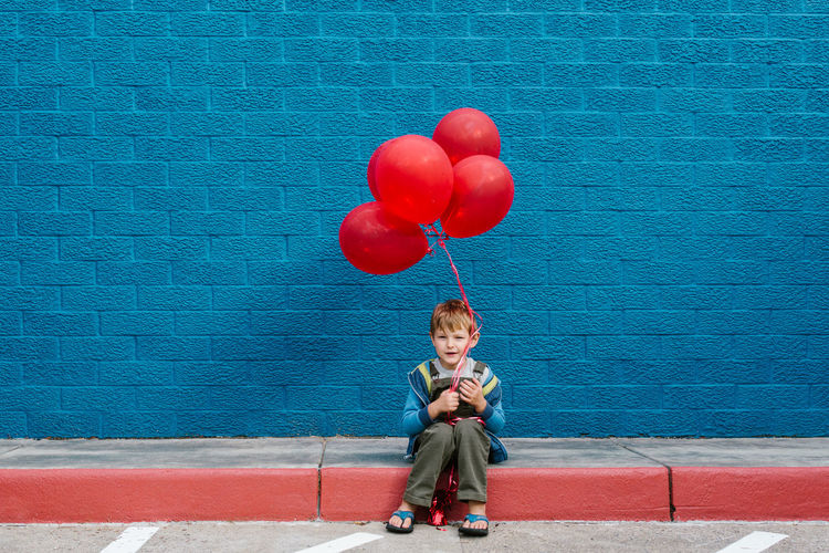 Full length of a boy sitting on balloon