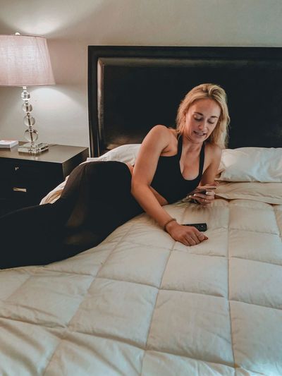 Young woman using mobile phone while relaxing on bed at home