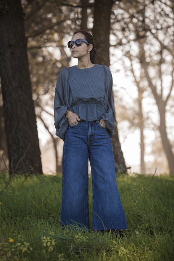 Young woman wearing sunglasses standing on field