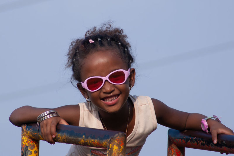 Portrait of happy girl wearing sunglasses against sky