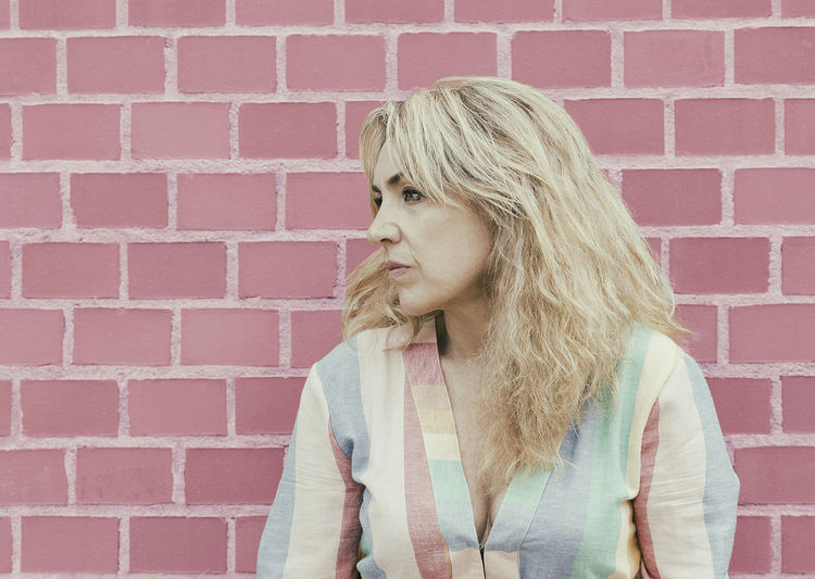 Blonde woman in front of a brick wall