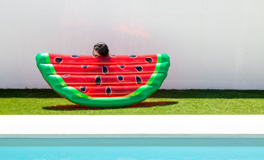 Portrait of girl hiding behind watermelon