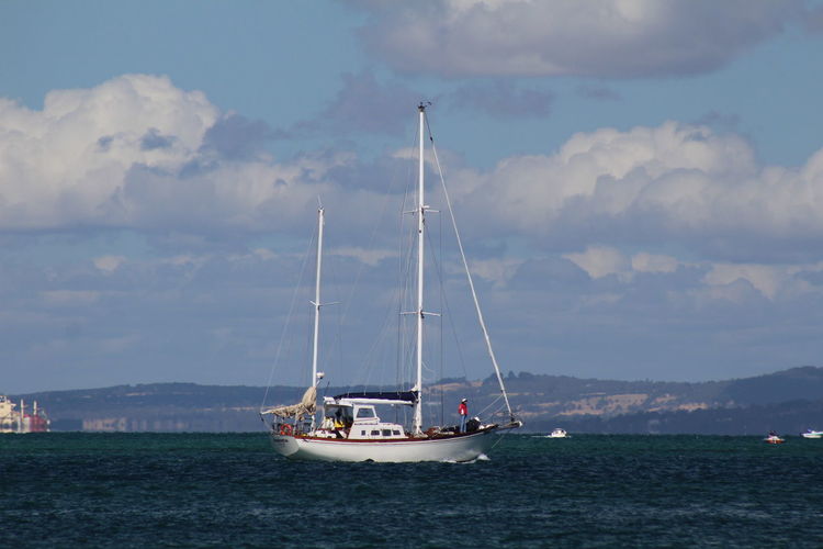 Sailboat on sea against cloudy sky