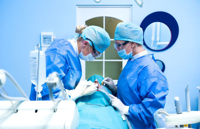 Doctors performing dental implantation in operating room