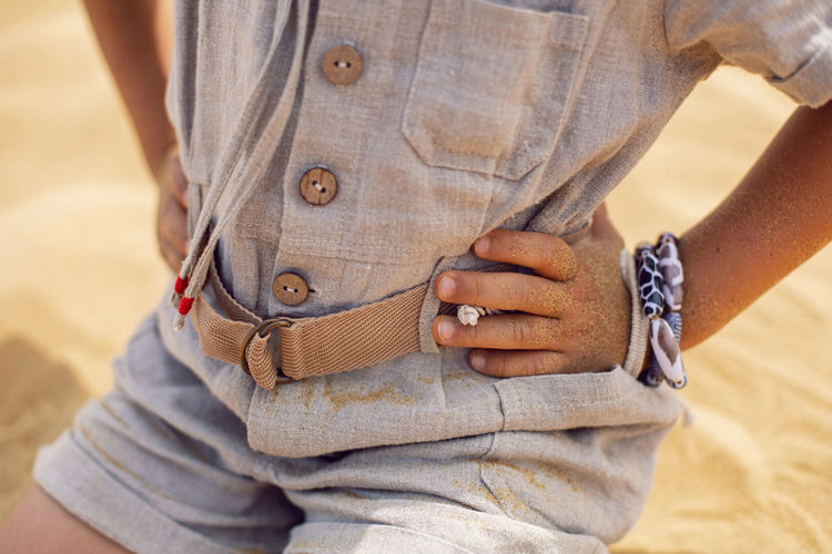 Child holds his hands on the belt of his costume from the moon while sitting in the desert on a dune