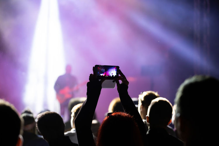 Rear view of people photographing at music concert
