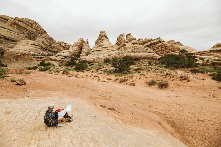 Hiker looks at the fins and checks his map on a hike in the canyonland