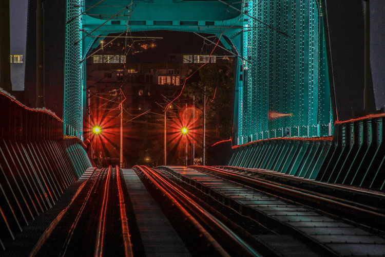 Railroad tracks in illuminated city at night