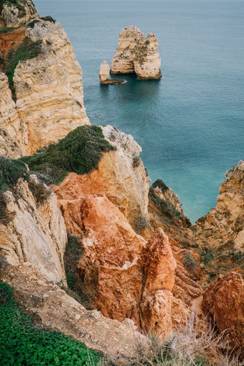 High angle view of rock formations by sea against sky