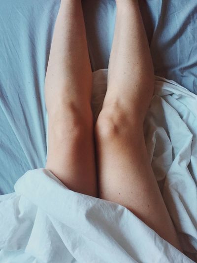 Low section of woman lying on bed