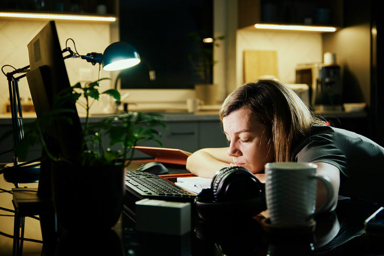 Tired woman works at home workplace