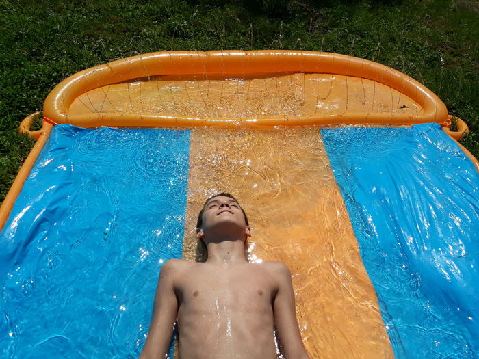 Shirtless boy lying in wading pool