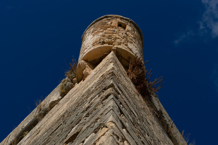 Low angle view of old tower against blue sky