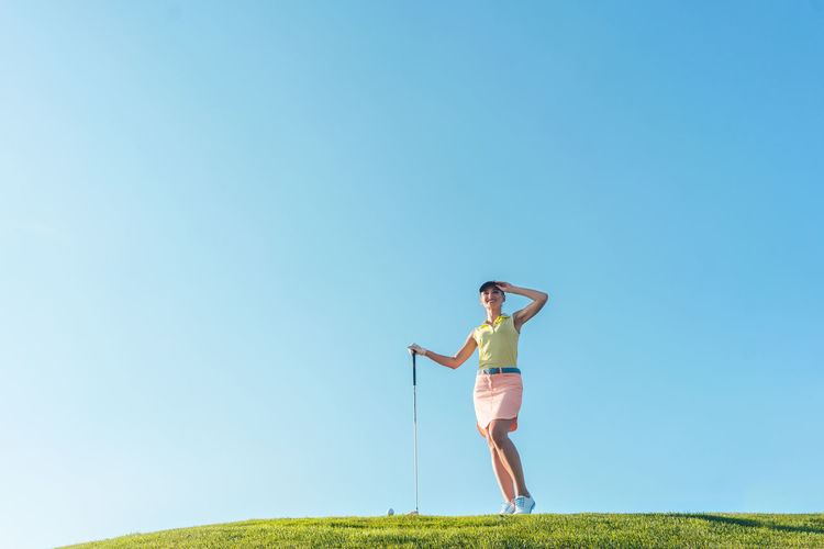 Smiling mid adult woman standing at golf course
