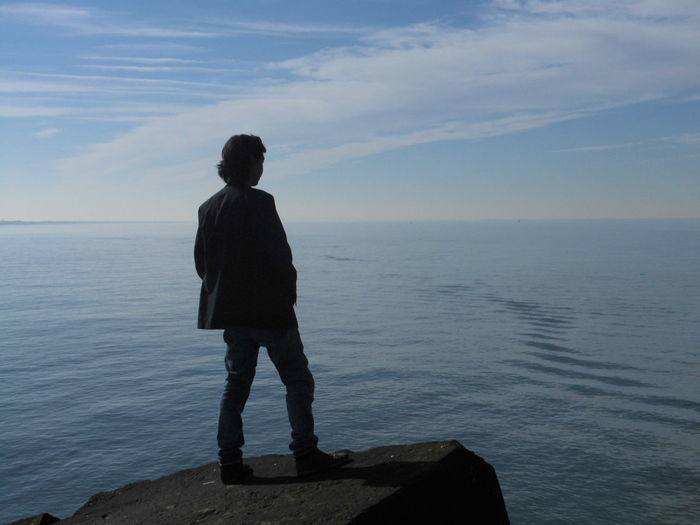 Rear view of man looking at sea against sky