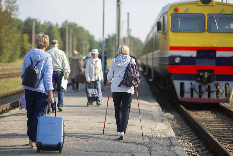 Rear view of a group of seniors elderly people waiting for a train to travel