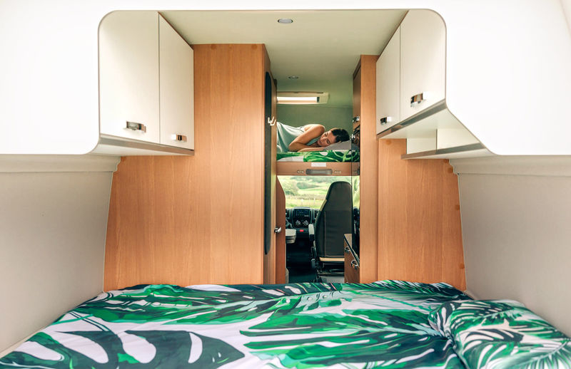 Woman sleeping alone on camper van bunk bed