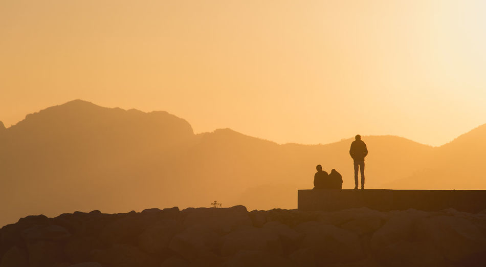 Silhouette people on mountain against clear sky during sunset