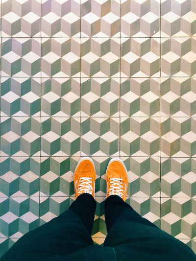 Woman in orange shoes standing on tiled floor 