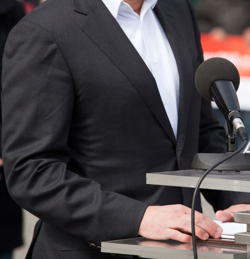 Midsection of businessman giving speech while standing at podium