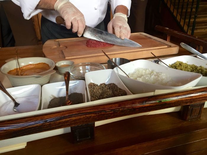 Midsection of male chef chopping beef on table at restaurant