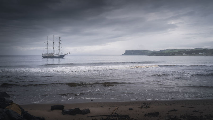 Dramatic storm sky rolling over anchored tall ship near northern ireland coast