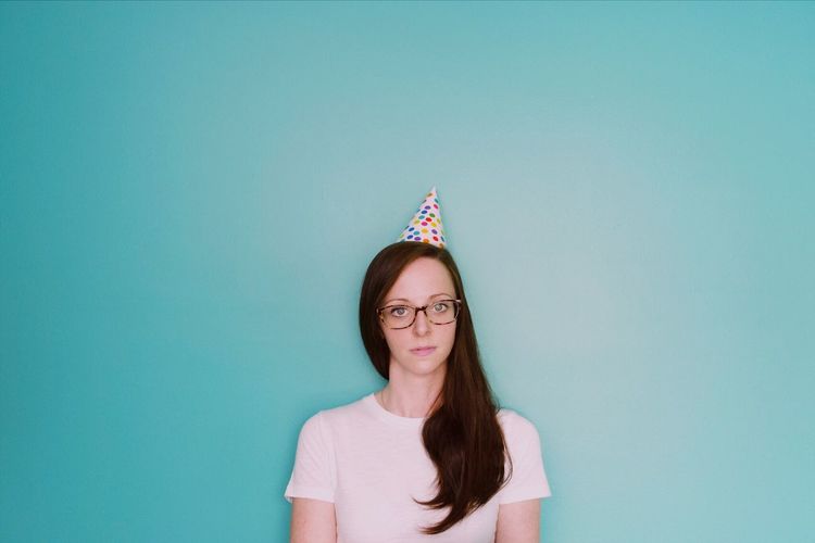 Portrait of young woman standing against blue background