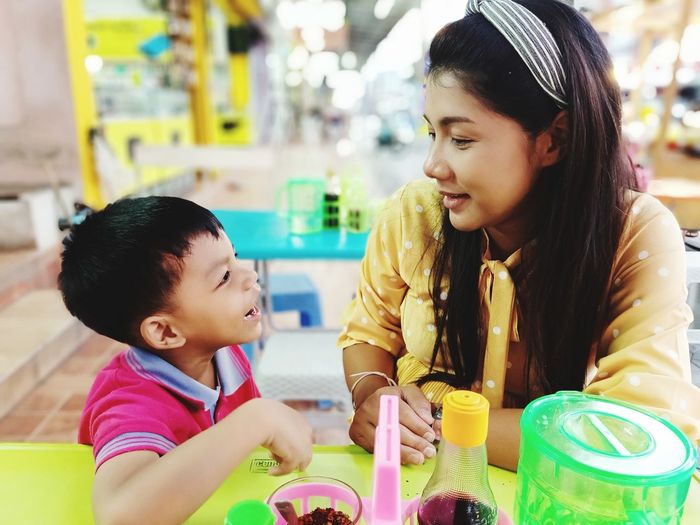 Close-up of smiling mother and son sitting at restaurant