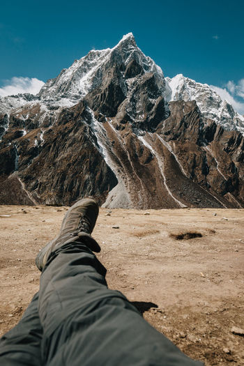 Low section of person sitting on landscape against mountain