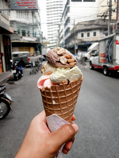 Hand holding ice cream cone on street