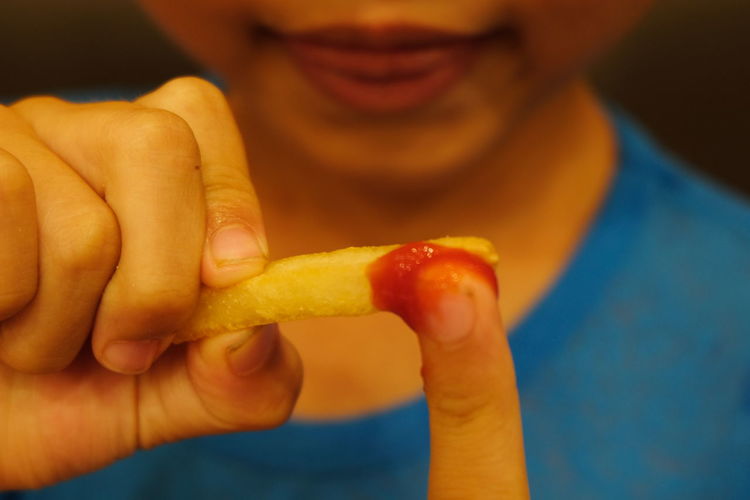 Midsection of boy eating french fries