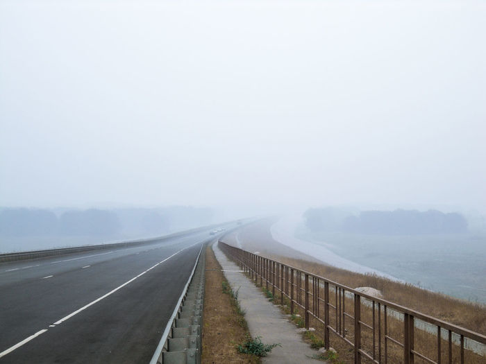 Road leading towards fog against sky